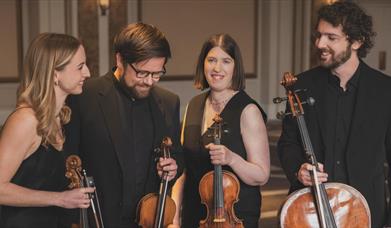 Castalian Quartet in formal black dress holding violins and cellos.