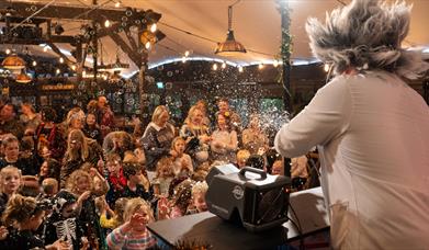 A man dressed as a crazed scientist entertaining a crowd of children with balloons at Dunkertons Cheltenham