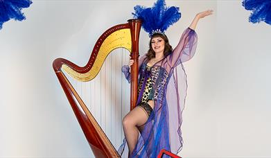 Sam Hickman in a showgirl costumer next to her Harp