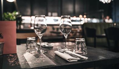 A set dining table at Brasserie Blanc Cheltenham, with two wine glasses and a menu