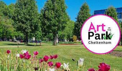 A photo of the imperial gardens park where art in the park will take place showing white and pink tulips in the foreground, tall green trees against a