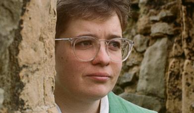 Cerys Bradley peering from behind a stone wall