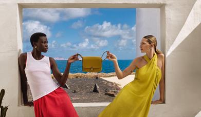 Two models holding a handbag