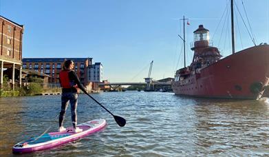 Paddle boarding on Gloucester docks in front on Sula Lightship